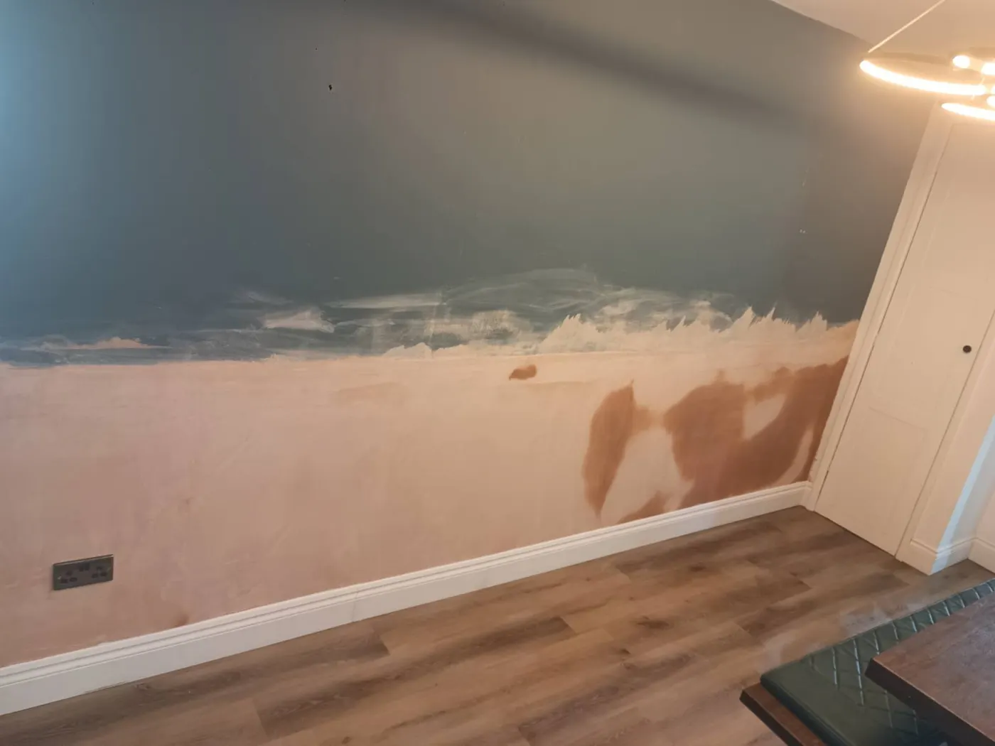 Freshly replastered lower walls in the living room after damp proofing, drying ahead of decoration