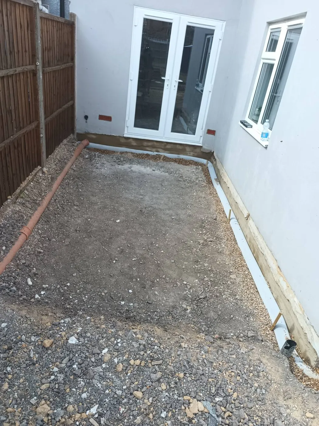 Trench dug along the back of the house for a new French drain