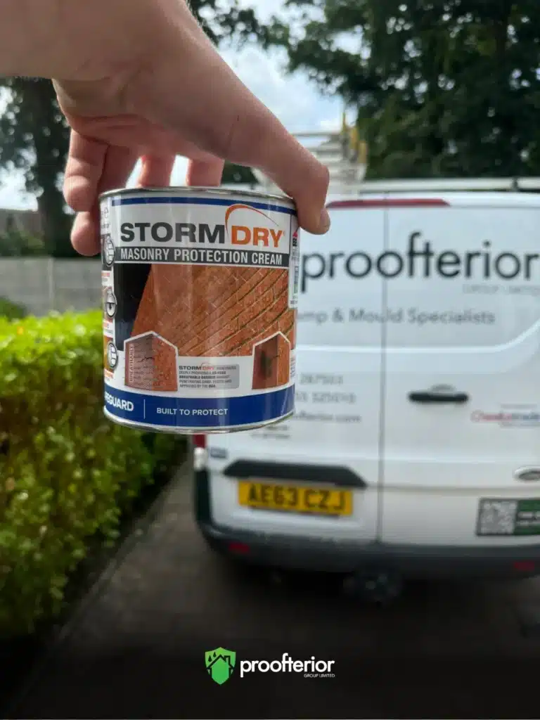 tormdry Masonry Protection Cream tin held in front of a Proofterior damp proofing van, ready for exterior wall treatment.