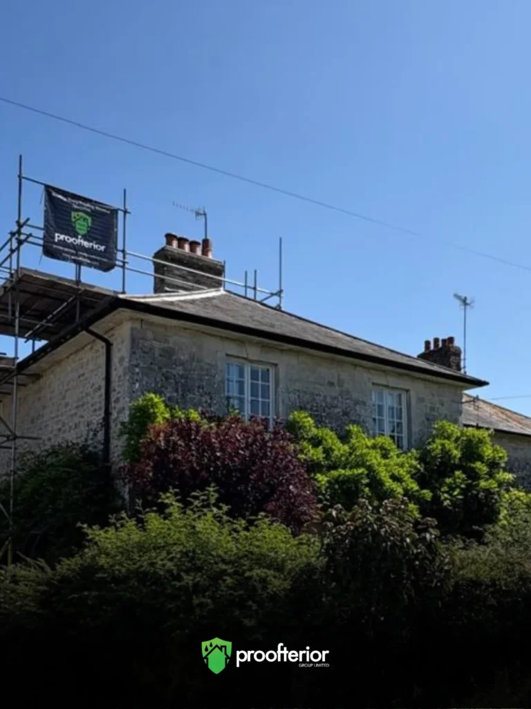 Stone-built house in Dorset under Proofterior scaffolding, prepared for damp-proofing and restoration work.