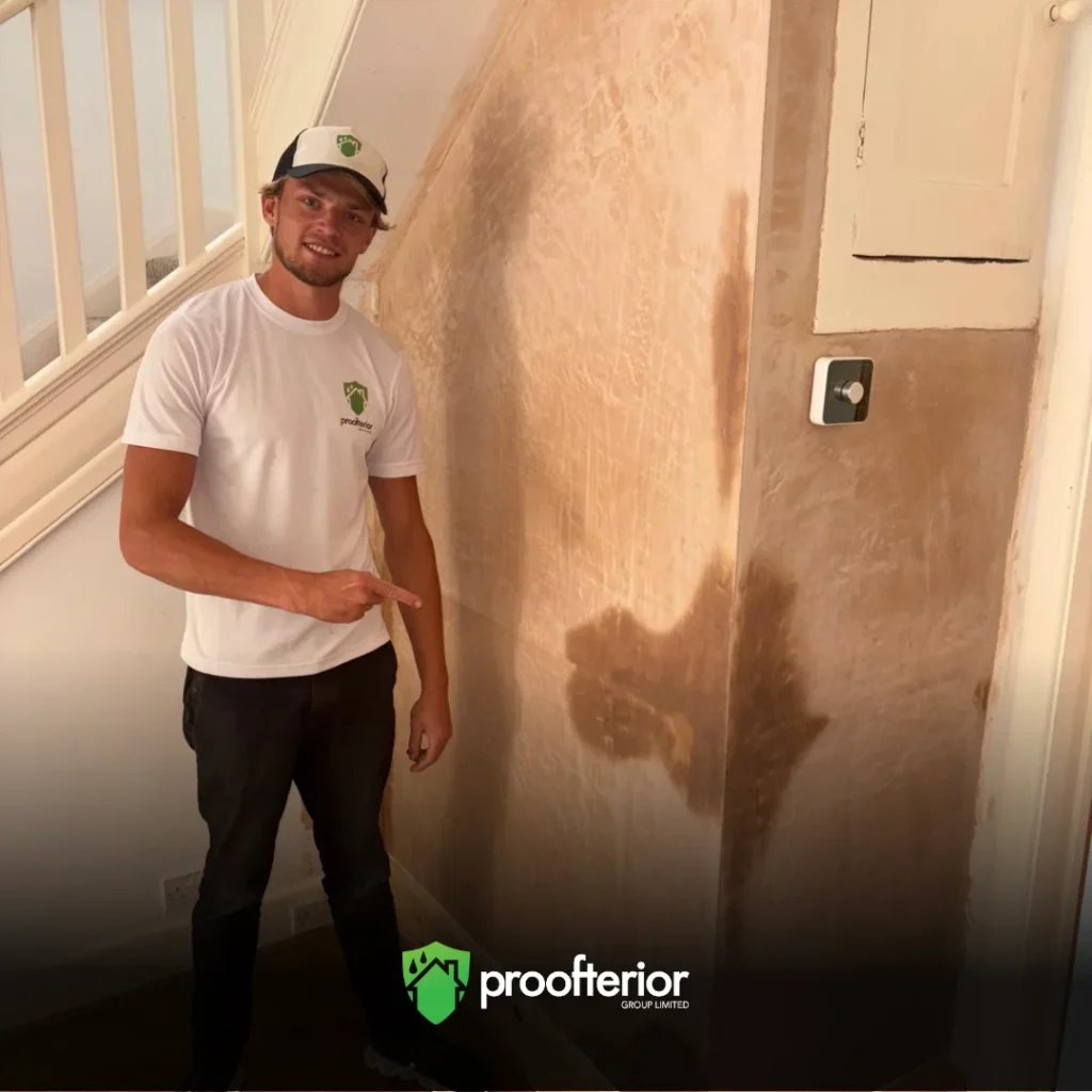 Proofterior damp proofing technician standing beside newly treated wall in Hampshire property.