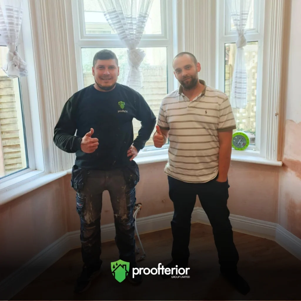 Proofterior damp proofing technician with happy Dorset homeowner beside freshly restored bay window wall.
