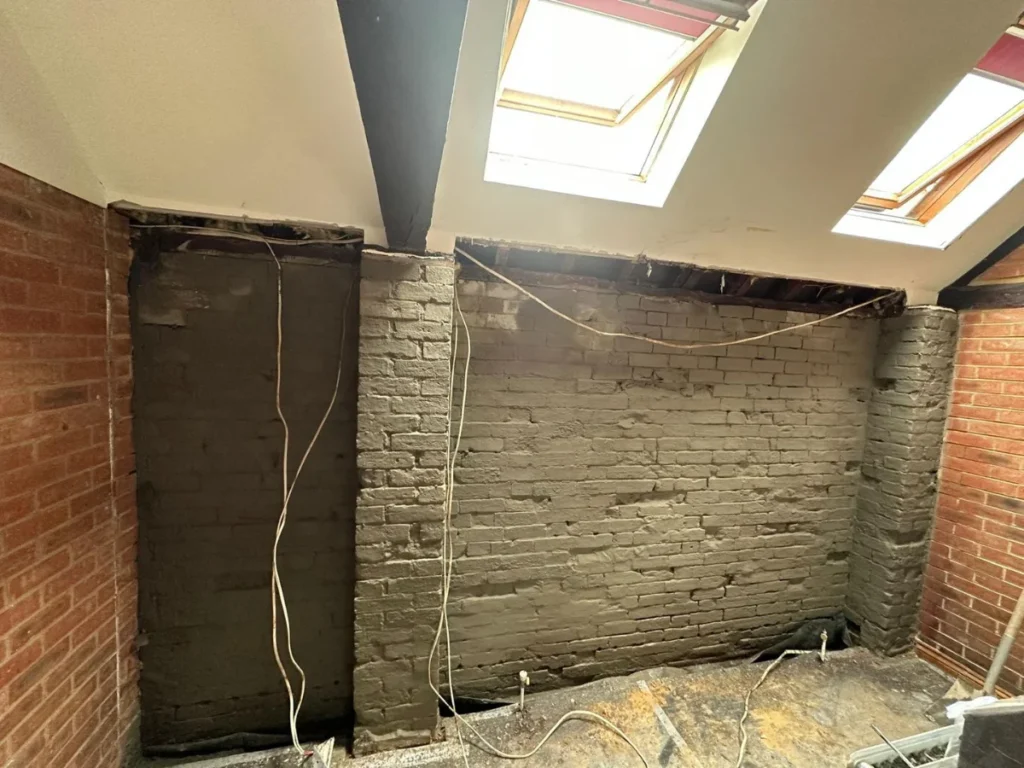 exposed brick retaining wall during damp proofing preparation in Dorset showing removal of plaster before waterproof membrane installation